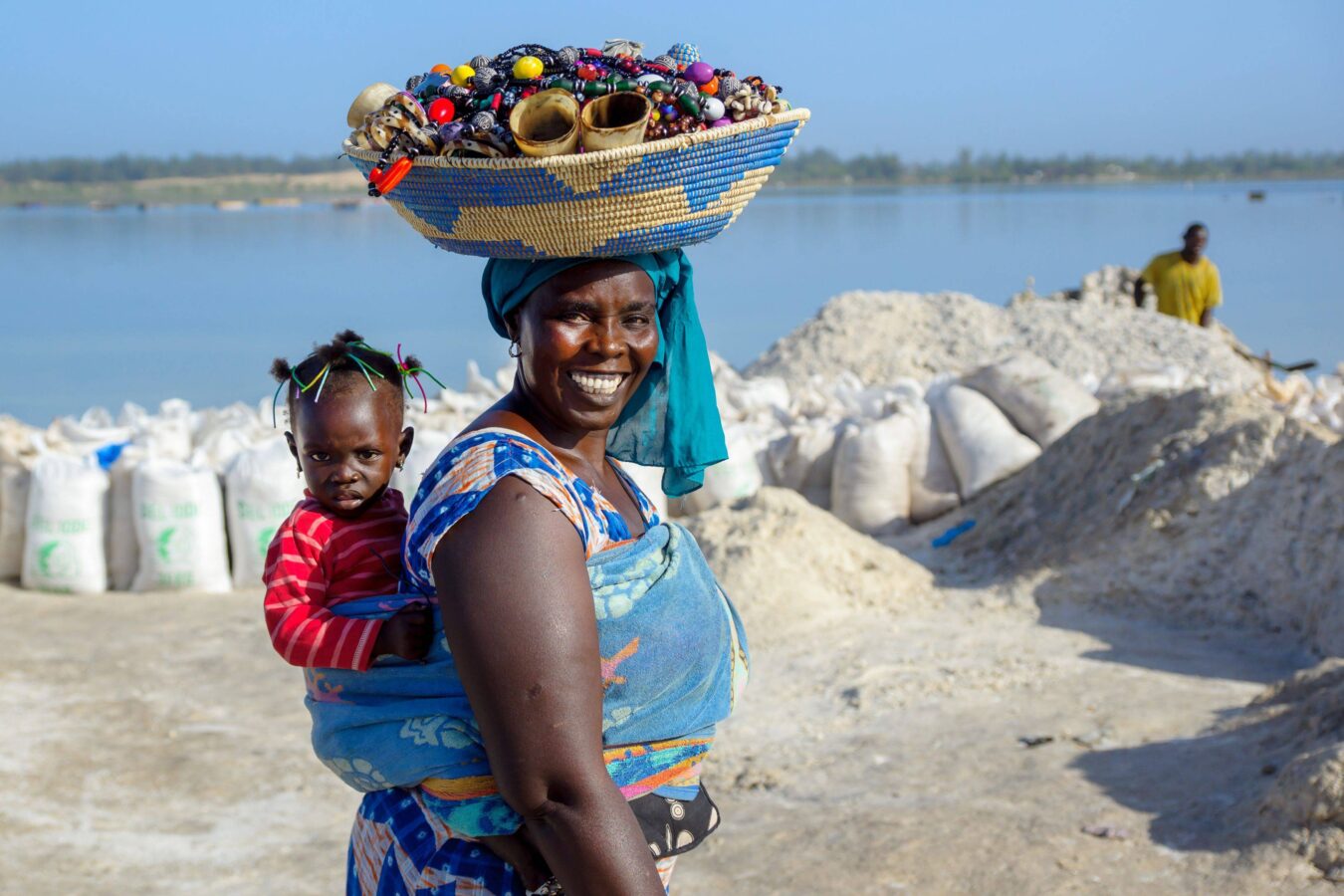 Femme travaillant dans la production de sel à Kaolack, avec son enfant sur le dos, au cœur de la région arachidière du Sénégal.