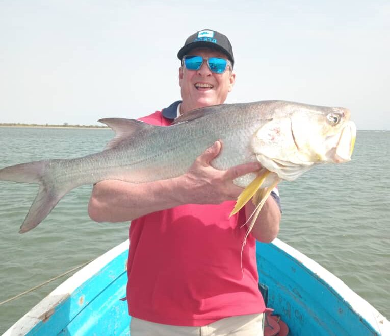 Pêcheur souriant tenant un gros capitaine à bord d’une coque ouverte dans le Sine et Saloum, pendant un séjour de pêche sportive avec Téranga Découvertes au Sénégal