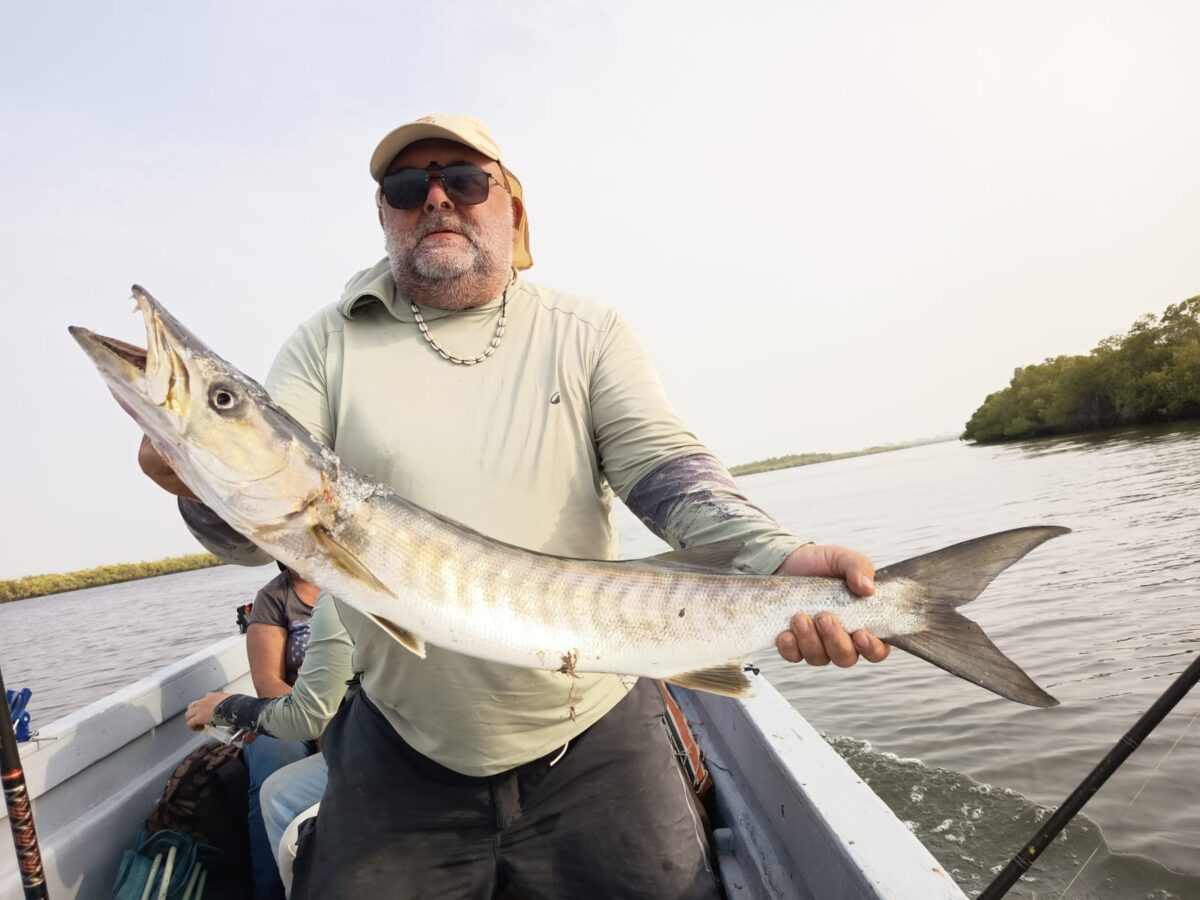 un pêcheur tenant un barracuda à la main sur le delta du Sine Saloum